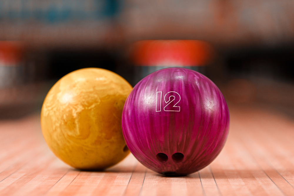 Two bowling balls sitting on a lane.