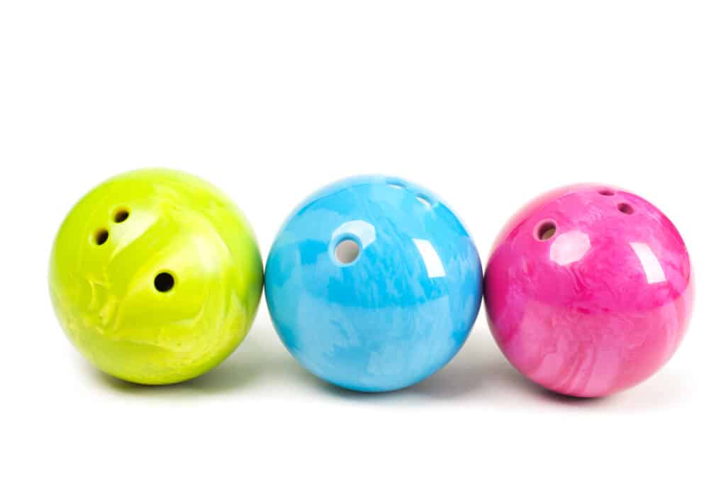 Three colorful ten-pin bowling balls; similar to the same ball colors that i found at my local bowling alley.