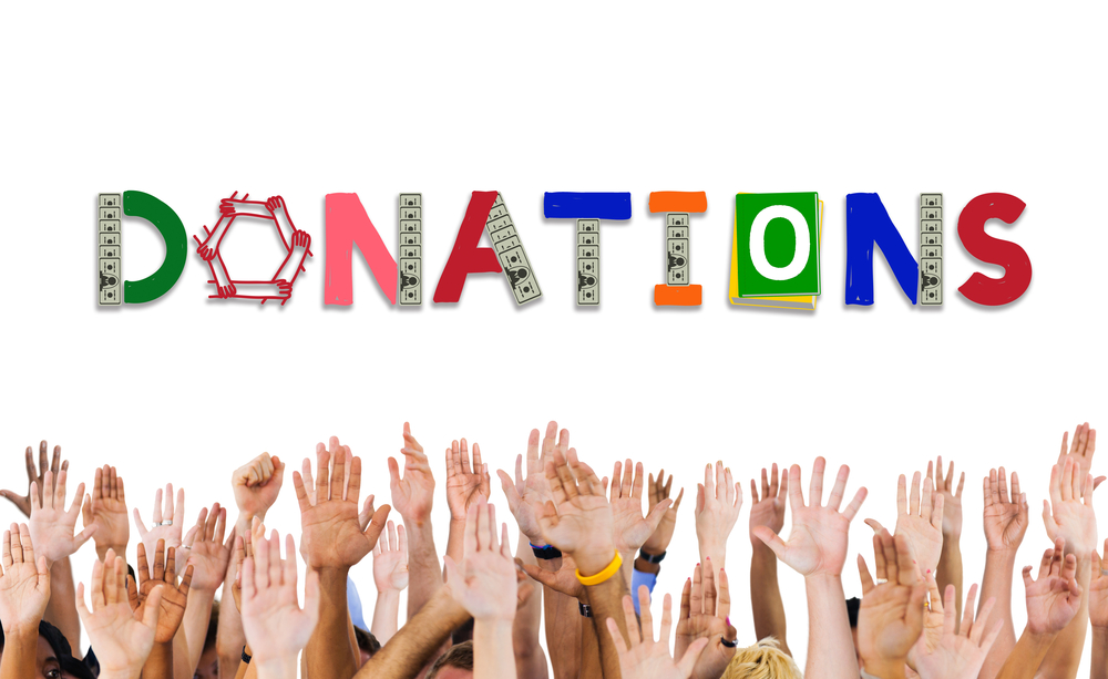 The word donations with people raising their hands in the air. Bowling balls can be donated to various charities and organizations.