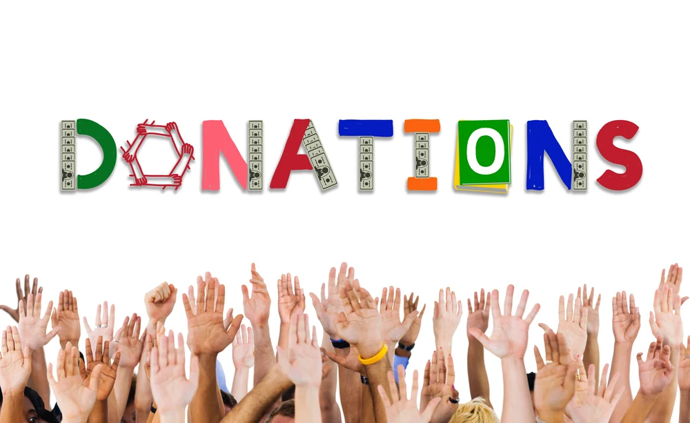 The word donations with people raising their hands in the air. Bowling balls can be donated to various charities and organizations.