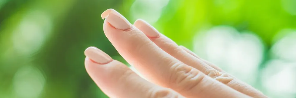 Lady's hand with acrylic nails. The middle finger nail is crack or chipped.