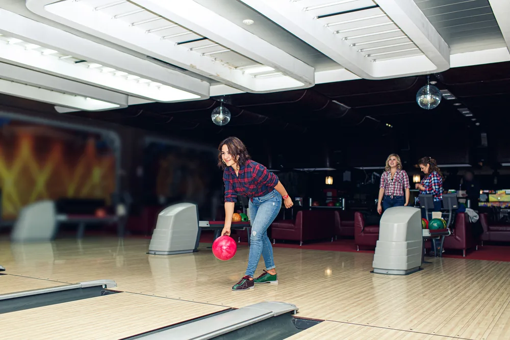 Beautiful girl plays bowling in bowling club
