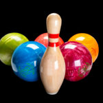 Various colored bowling balls on black background with tenpin bowling pin in the center