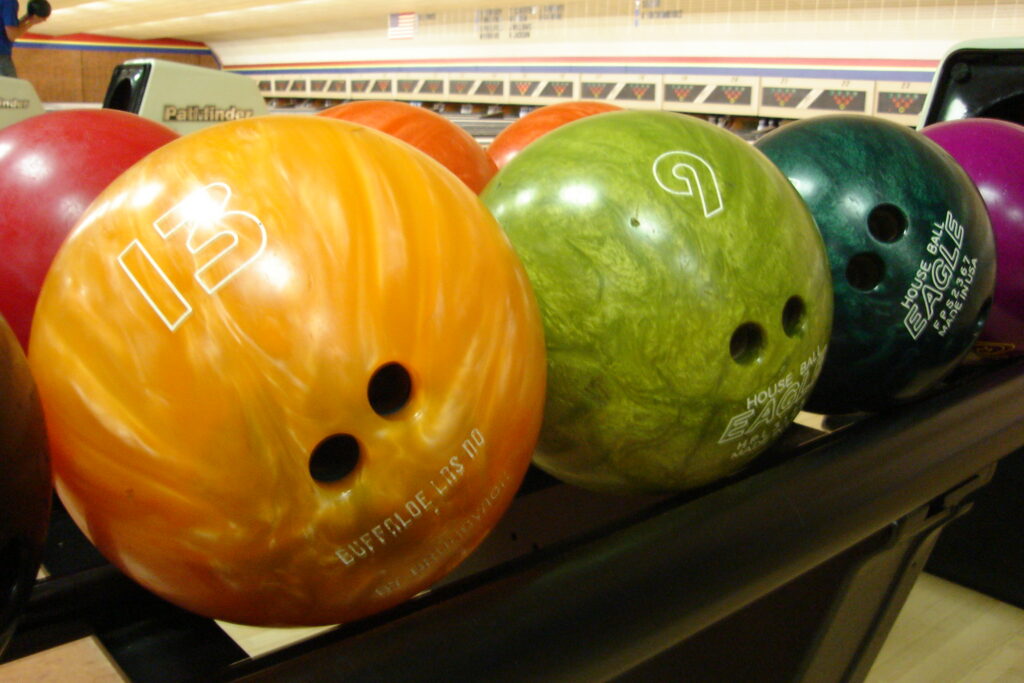 This image is of several multi-colored balls on a bowl return. The bowling ball shape is perfect for fitting between the standard space betten the pins.