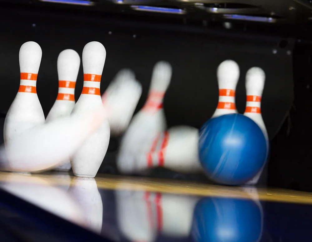 Blue bowling ball hitting motion blurred pins at a pro tournament.