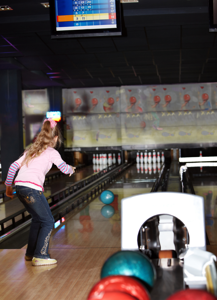 This image is of a little girl using bumpers to bowl.