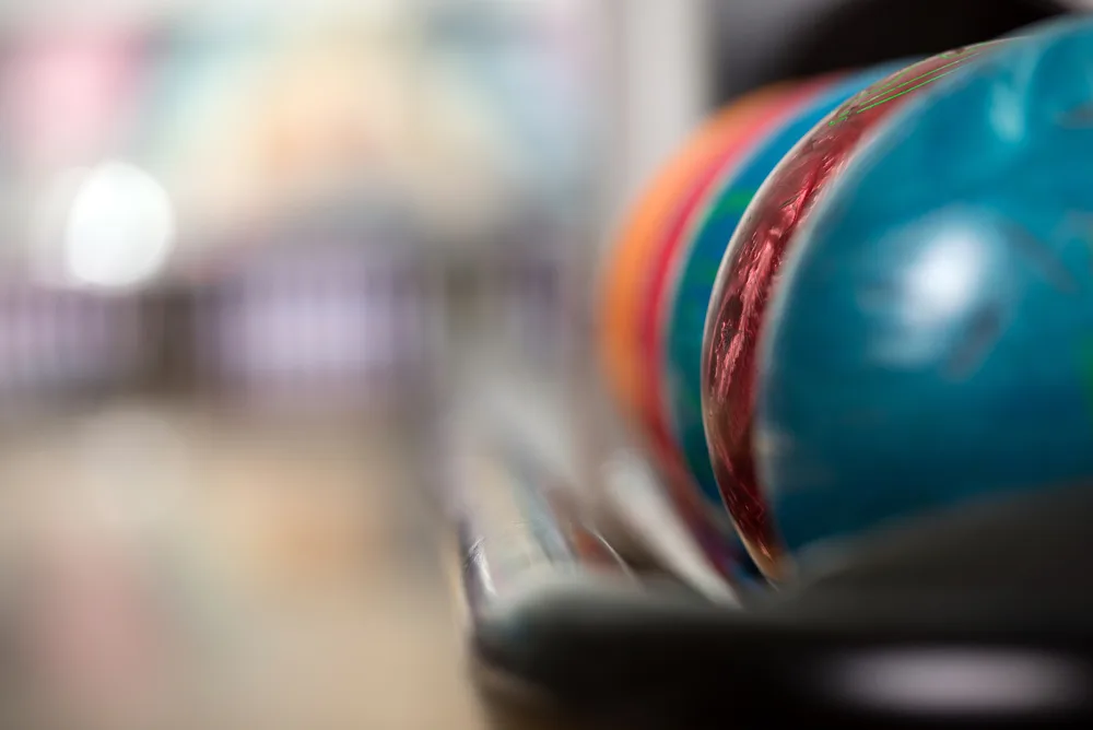 Colored bowling balls on a ball return that have been surfaced with new grit pads that affects how the ball reacts.