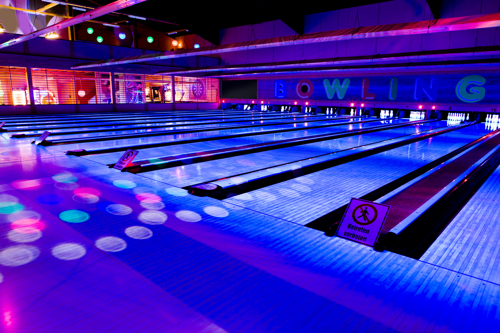 A local cosmic bowling alley with runway lights, strobe lights and multi colored lights.