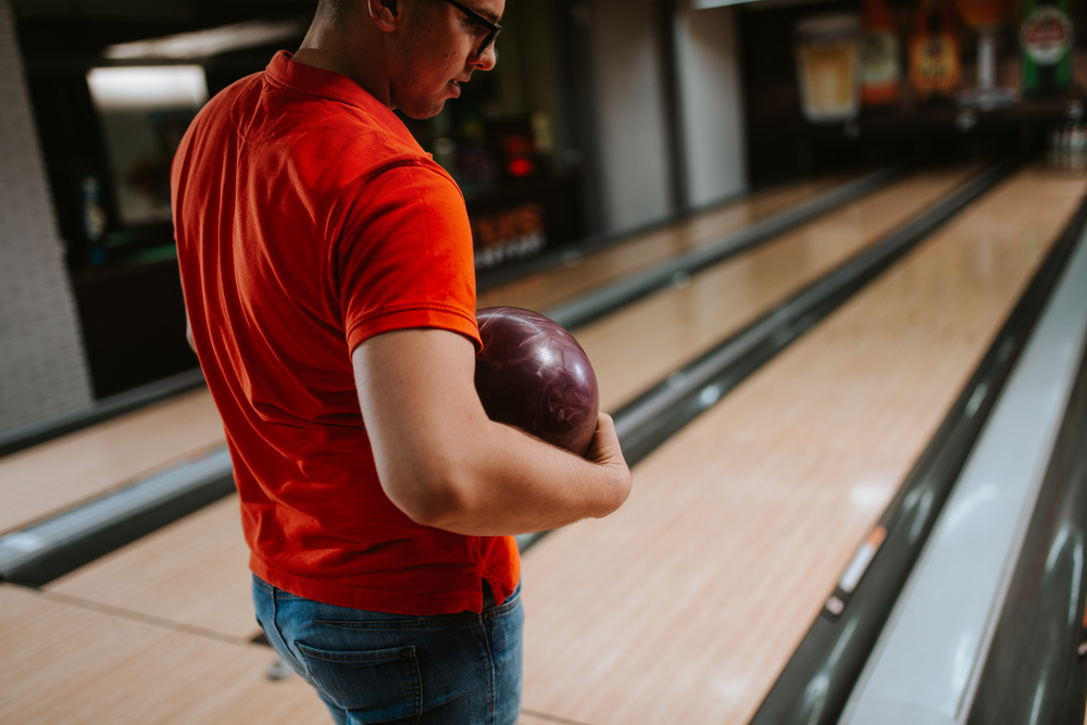 A casual bowler that normally bowls with reactive resin balls uses a plastic bowling ball at a local bowling lane.