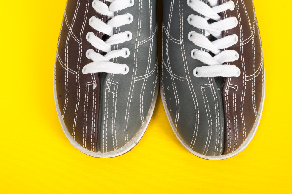 Two colored shoes, gray and burgundy, on a yellow background. These clean shoes were cleaned in the laundry machine with mild detergent.