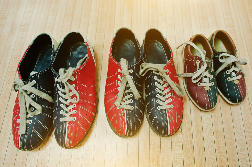 Three pairs of dual-colored, red and blue bowling showing against a pinewood bowling lane are fashion trends among professional bowlers.