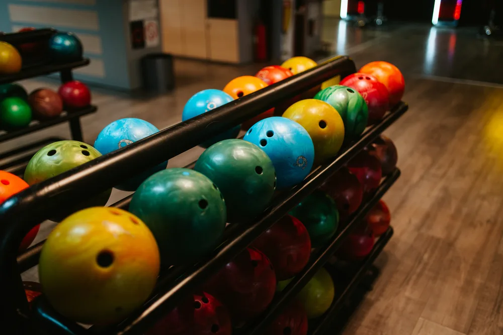 A bowling ball return with plastic and reactive resin bowling balls outside of the bowling pro shop.