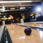 A reactive resin bowling ball rolling down the lane during a competitive bowling game on an oily lane surface.