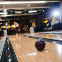 A reactive resin bowling ball rolling down the lane during a competitive bowling game on an oily lane surface.