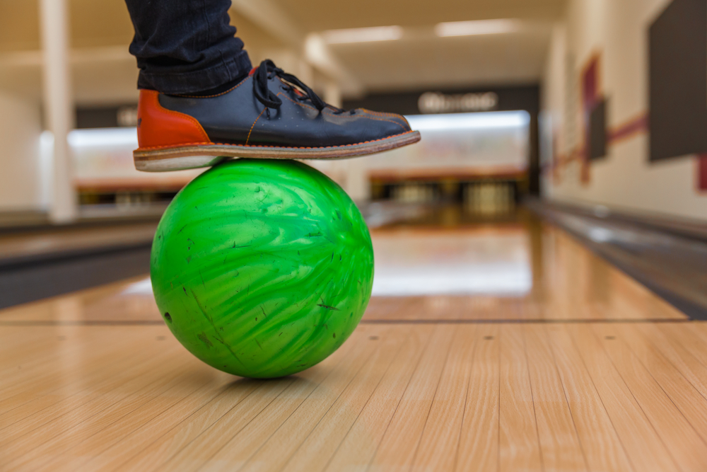 Bowling shoes and ball for a bowling game are positioned in front of the foul line on the lane.