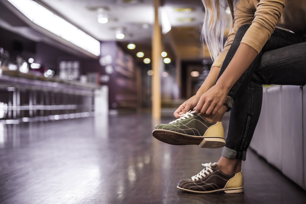 A lady that decided to rent and wear shoes at the alley instead of purchasing her own performance bowling shoes.