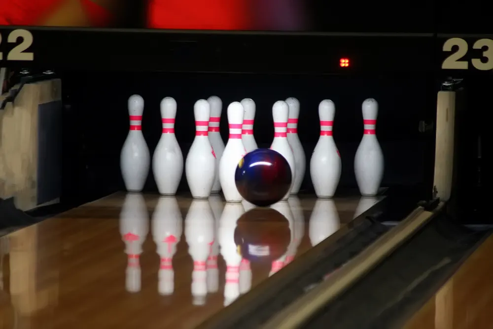 A bowler throws a perfect pocket shot after almost getting his fingers stuck in the ball as he releases a perfect strike.
