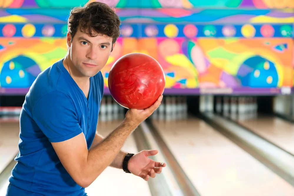 A man holding a 12-pound ball, wondering if it will sink or float since heavy things sink most frequently.