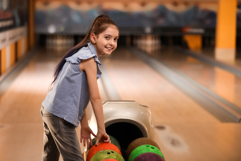 This image is of a little girl standing at the return for the bowling balls. A good bowling average school for 10 to 12 is 70 to 120.