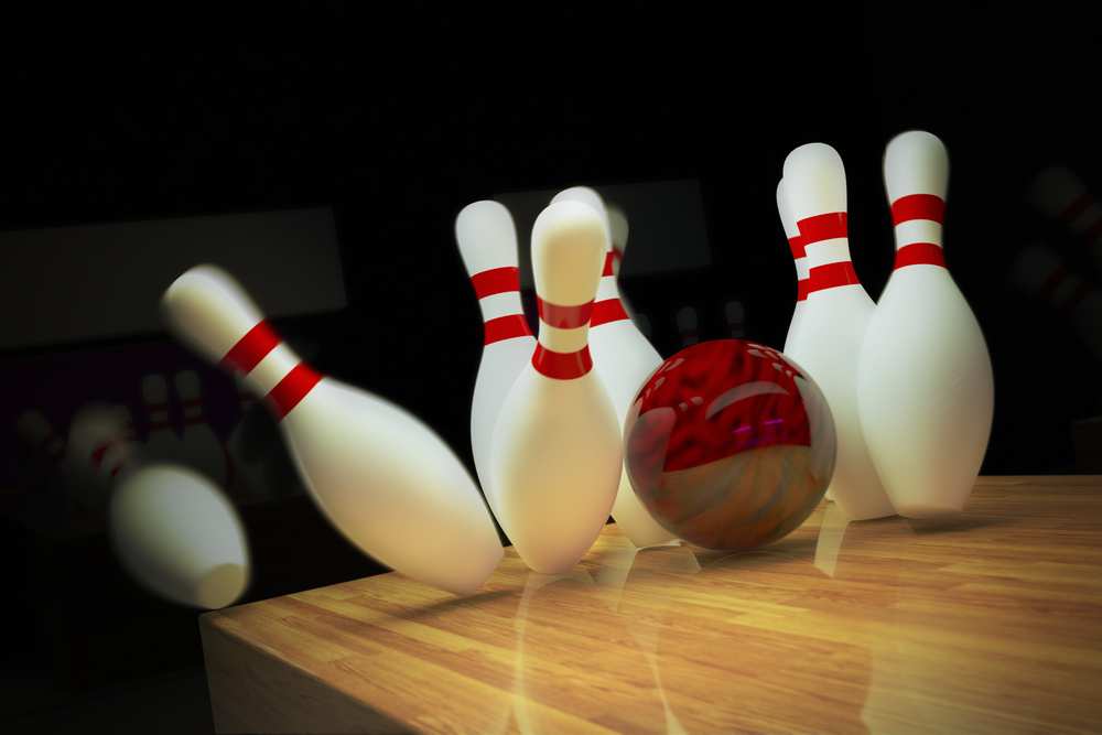This image shows a red bowling ball knocking down pins for a strike.