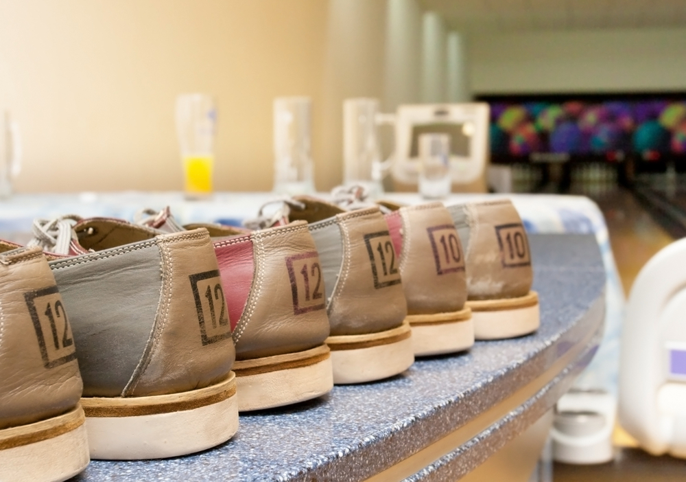 Multiple pairs of shoes in a line on a countertop at the local bowling shop. The shoes were disinfected and are sitting in a dry and cool place.