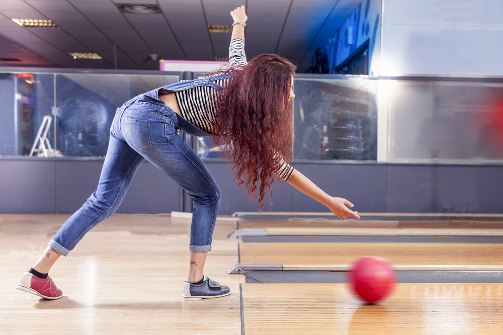 A young female playing a game of nine-pin no-tap bowling where leaving the corner pin still counts as a strike.