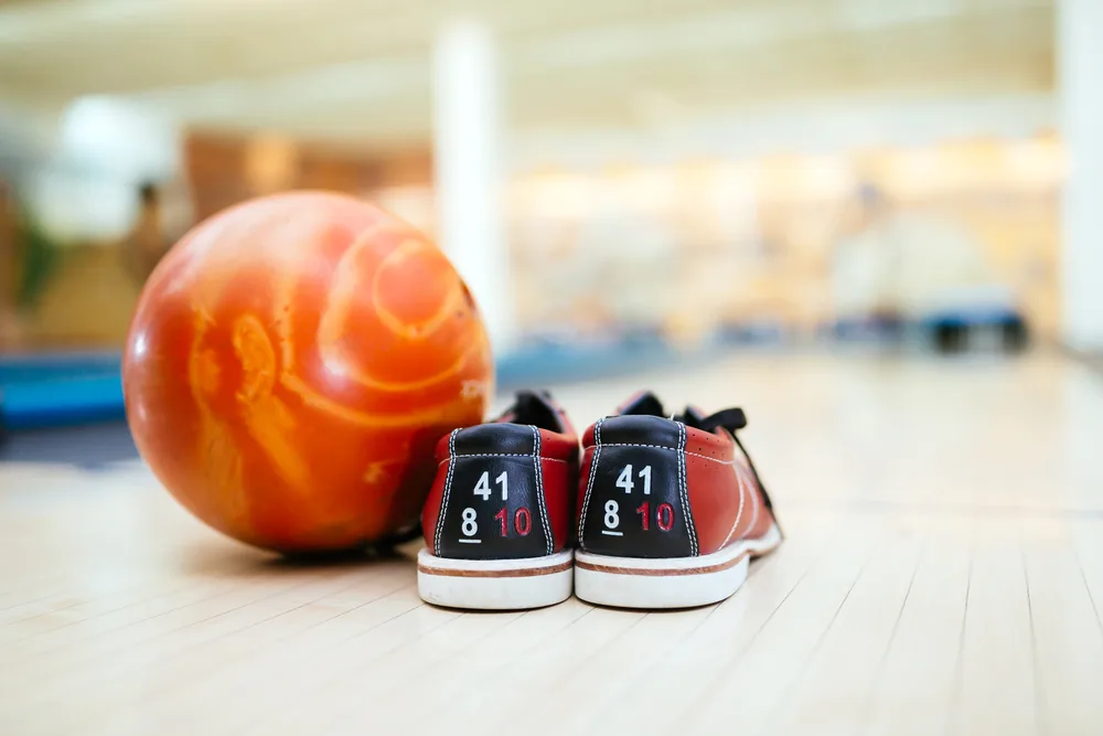 The blue and red shoes next to the orange ball is sticky. A sticky bowling shoe can ruin your game, so switch shoes or use shoe covers if necessary.