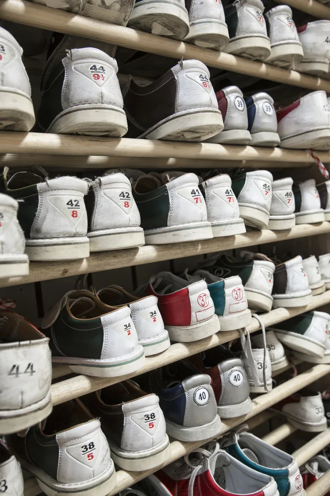 A wall display of various colored and sized bowling shoes at a local alley where the attendant disinfect bowling shoes with chlorophyll formalin and benzalkonium and formalin and benzalkonium chloride.