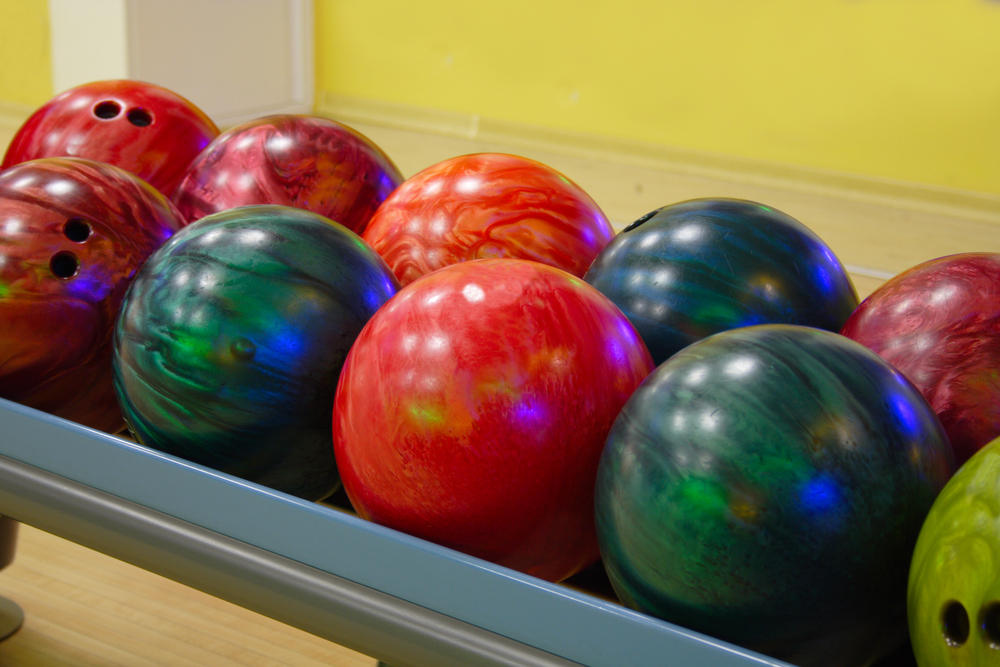 Ten bowling balls sit on a ball return as they were just polished by pro shop operator at a local bowling alley.