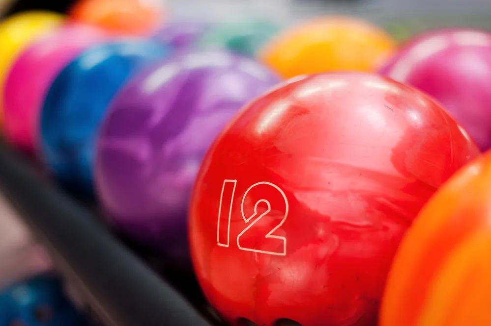 Variety of colors. Close-up of a storm ball that's bright red lying in the rows of other colorful balls.