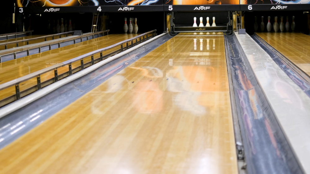 On a polished bowling lane, imagine your own ball as a tennis ball; using the fingertip grip, the ball rotating down the lane in a curving pattern.