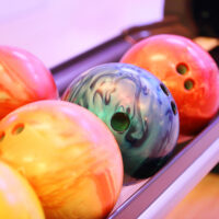 A row of reactive resin bowling balls and plastic bowling balls on the ball return.