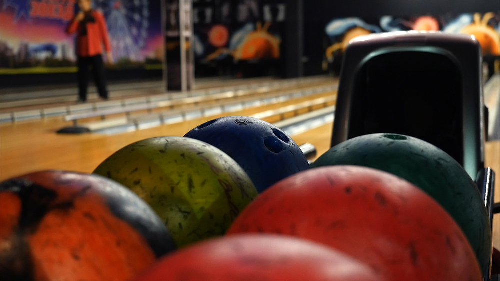 Bowling staff member walks up and down each lane, with the bumpers erect and ball return full of colorful balls. They are preparing for the local schools to come and bowl for college credit.