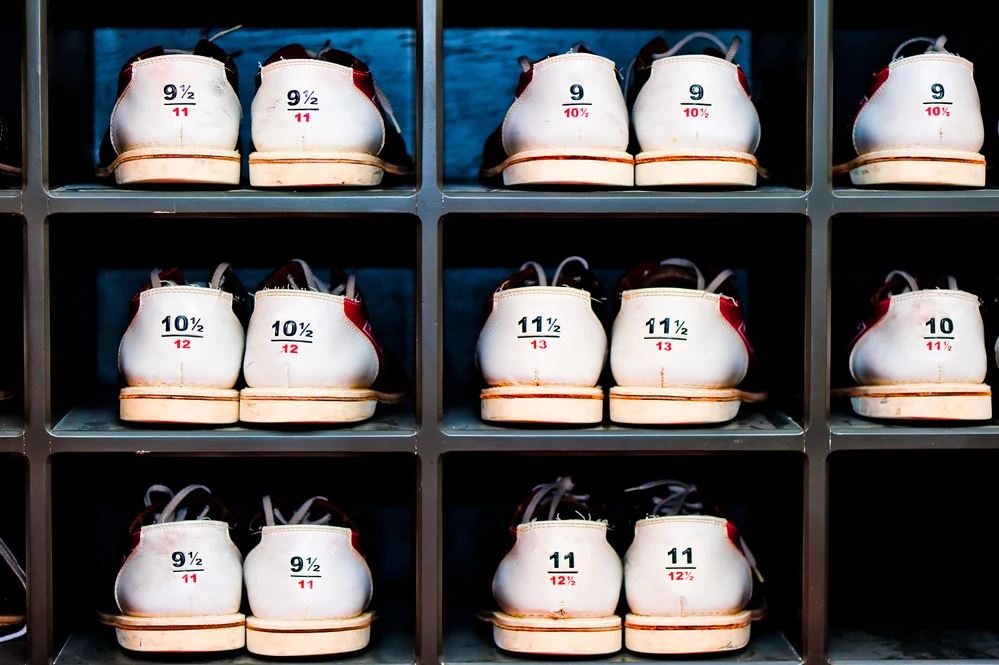 Wall display of various bowling shoe sizes and colors where the bowling alleys clean shoes with antibacterial spray with active ingriedients chlorophyll in a spray bottle to combat bacteria and fungi.