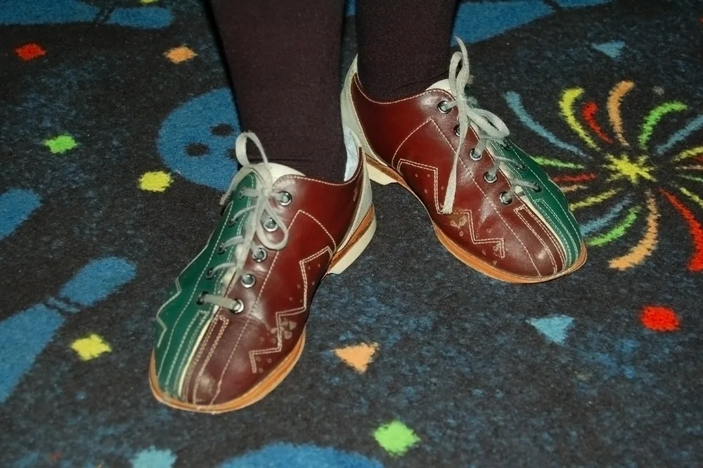 Tri colored, red,green and tan, bowling shoes where the bowler is wearing socks to help mitigate fungal infections.