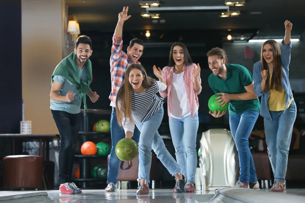 Six people, three guys and three girls are bowling. Up to eight people can play on a single lane, comfortably.