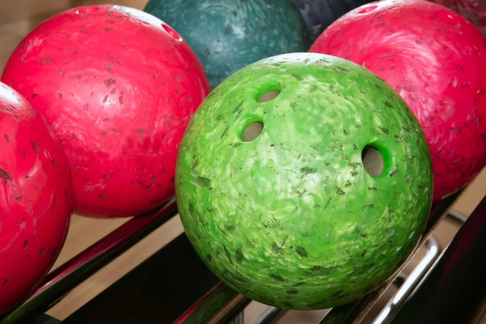 Upclose on several house bowling balls that all have debris and nicks on them.