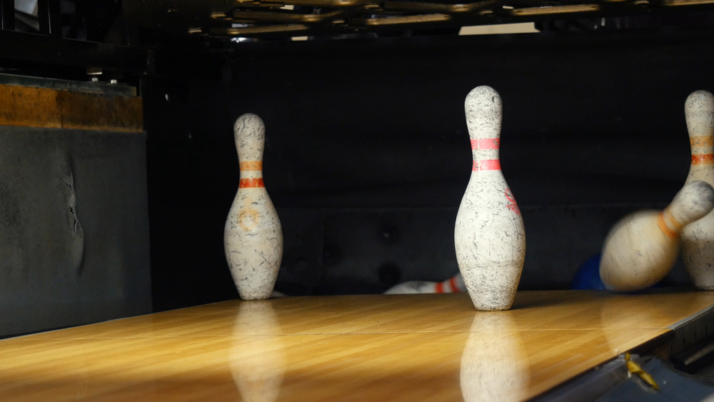 View of bowling pins standing in the third row of the bowling alley because the right handed bowler left pins standing when they attempted to clear the split conversions.