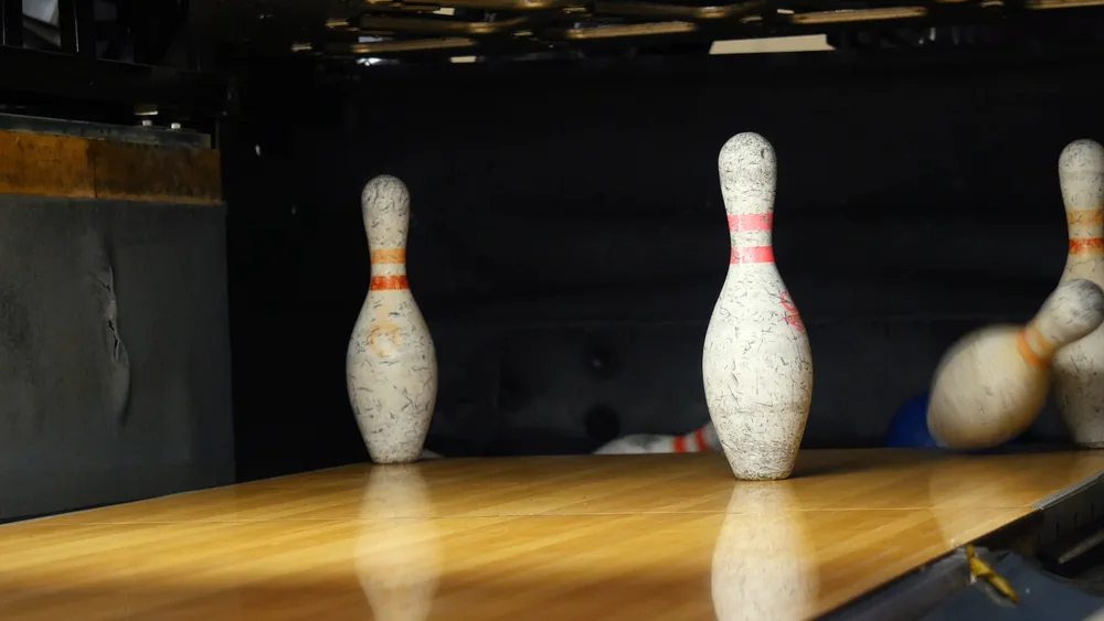 View of bowling pins standing in the third row of the bowling alley because the right handed bowler left pins standing when they attempted to clear the split conversions.
