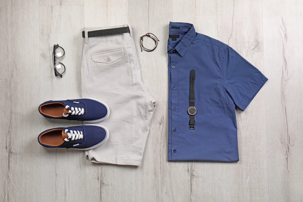 Belted khaki shorts and a blue button-down shirt, accessorized with a watch and twine bracelet. Such an outfit is suitable for bowling and a casual restaurant.