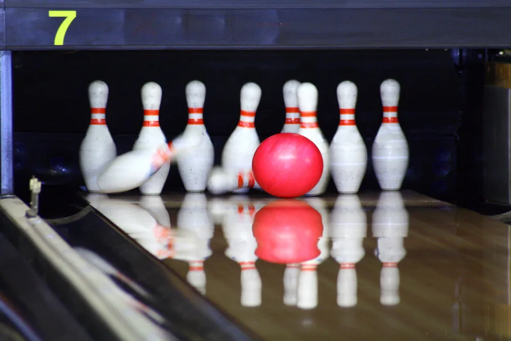 The bowler rolls their pink ball down the bowling lane into the ten standing pins. Pins knocked are bonus pin count for the previous frame.