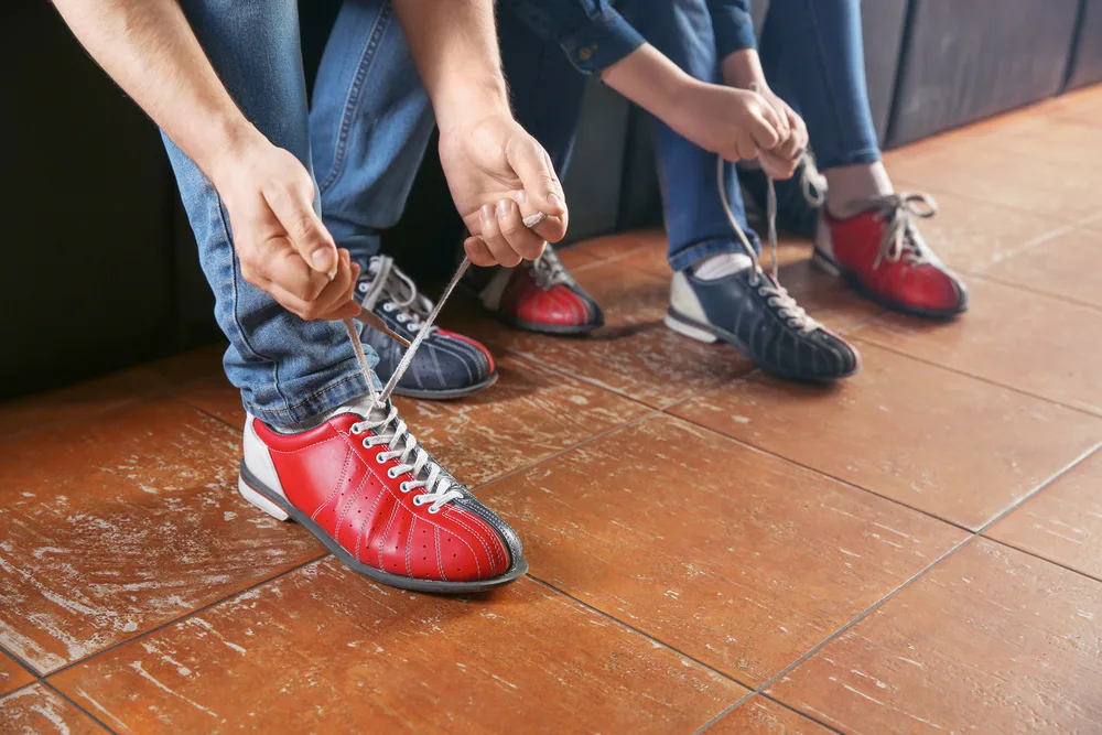 Family changing shoes before playing bowling at the alley and they sprayed their bowling shoes spray into each shoe themselves.