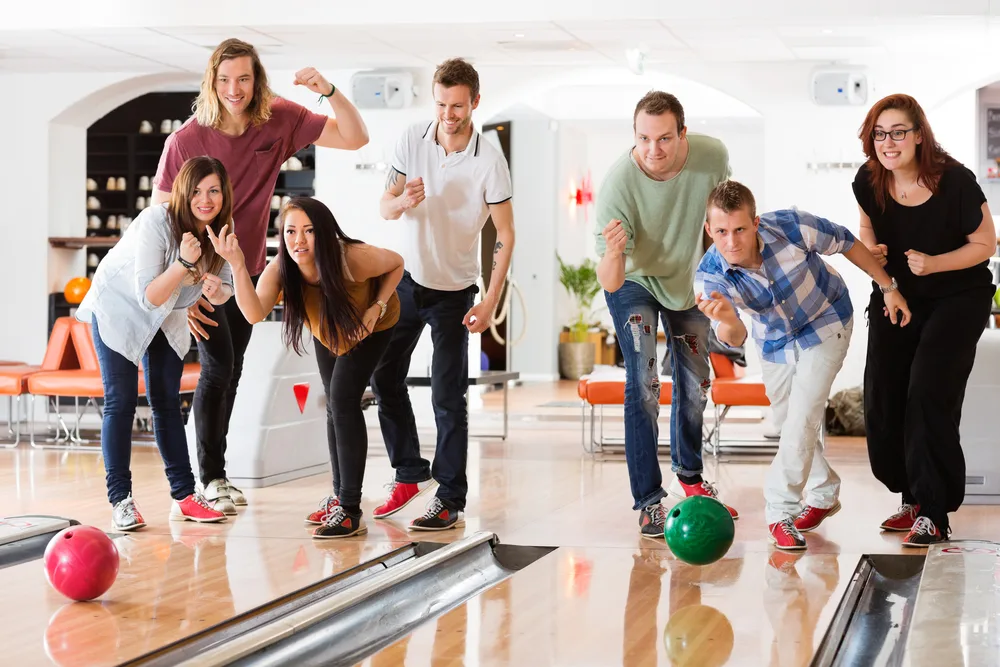 Seven friends, three women and five males use two lanes to bowl.