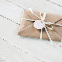 Gift vouchers or gift certificates on white wood background, wrapped in brown paper with a white bow are great gift ideas.