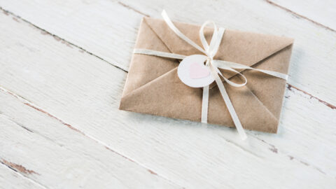 Gift vouchers or gift certificates on white wood background, wrapped in brown paper with a white bow are great gift ideas.
