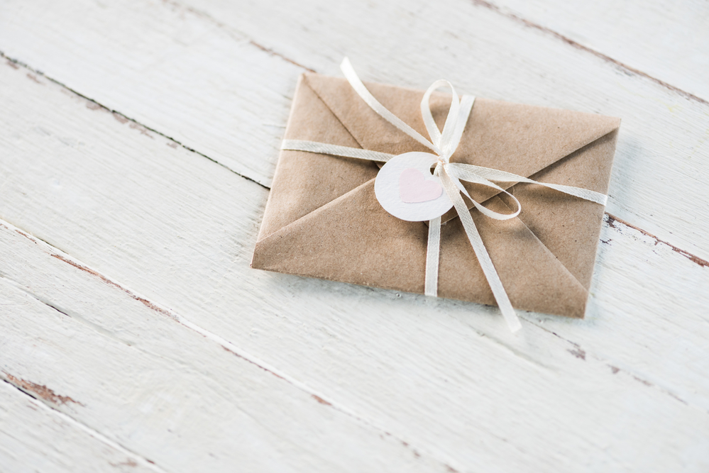 Gift vouchers or gift certificates on white wood background, wrapped in brown paper with a white bow are great gift ideas.