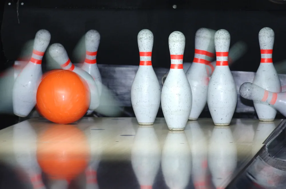 The professional bowler missed the diamond cluster with their orange bowling ball leaving an open frame.