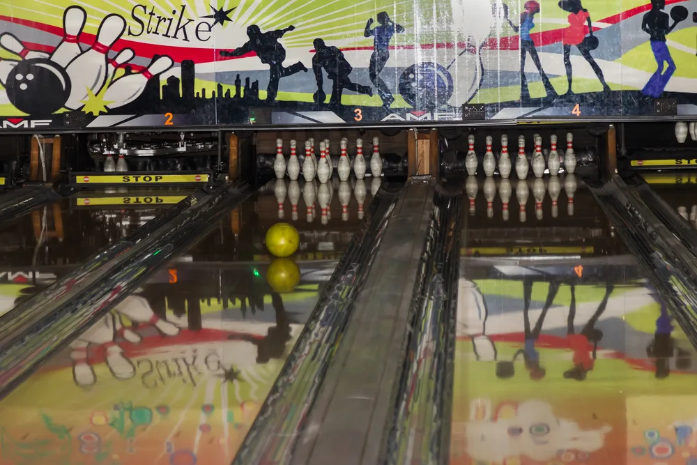 In the homemade bowling lanes, the pins of the bowling are lowered at the end of the track when the ball is returned. The pin setter is resetting pins after a throw in a distant lane.