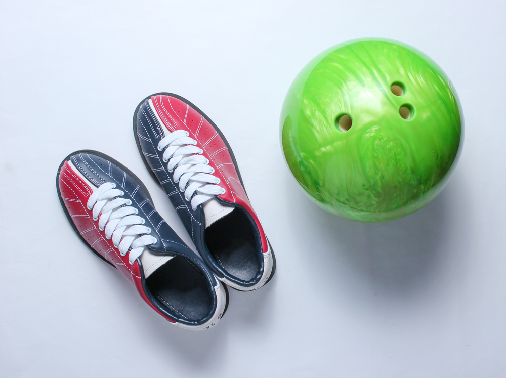 Bowling shoes with a green bowling ball on a white background have been sprayed with bowling shoe spray because they have been worn and considered dirty bowling shoes.
