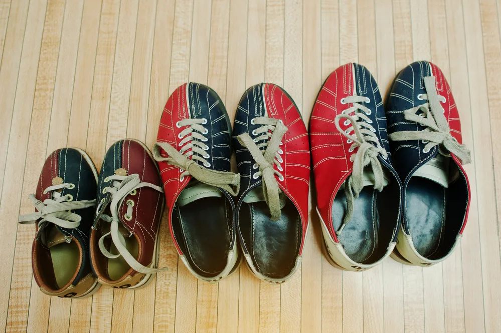 Three pairs of tri-colored bowling shoes typically at bowling centers that use a sanitizing deodorant spray.